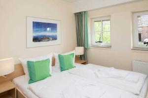 1 dormitorio con 1 cama blanca y 2 almohadas verdes en FEWO Ringelblume, en List