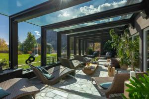 a patio with a lot of windows and chairs at Alp Wellness Sport Hotel Panorama in Fai della Paganella