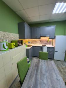 塞爾吉耶夫的住宿－Хостел Матрешка，厨房配有绿色橱柜、木桌和绿色椅子