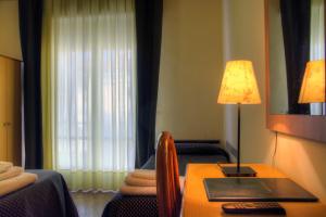 a hotel room with a bed, desk and lamp at Hotel Savoia in Finale Ligure
