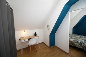 Cette petite chambre dispose d'un bureau, d'un lit et d'un mur bleu. dans l'établissement Appart'hôtel Le Pin, à La Tour-du-Pin