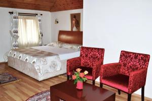 a bedroom with a bed and two chairs and a table at Hotel Villa Tafaj in Tirana