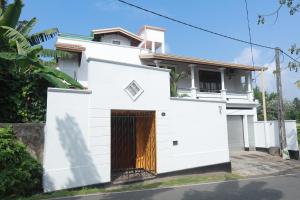 een wit huis met een bruine deur bij Villa 59 in Galle