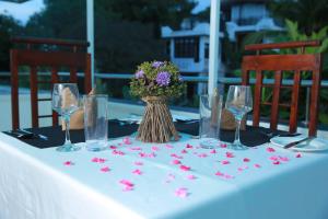 Una mesa con un mantel blanco con un jarrón de flores. en Villa 59, en Galle