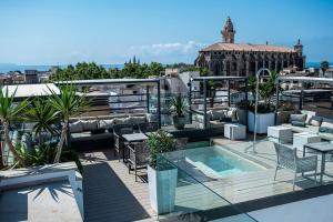 a rooftop patio with a pool and tables and chairs at Palma Suites in Palma de Mallorca