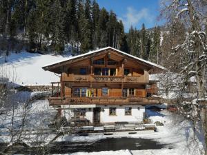 eine Blockhütte im Schnee mit Bäumen in der Unterkunft Farnreit in Brixen im Thale