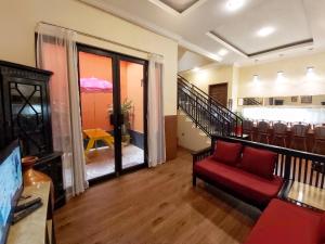 a living room with a red couch and a staircase at TAMA Guesthouse 15 People for Family or Group in Tangerang