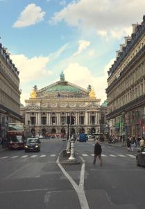 a large building in a city with a person crossing the street at Lovely parisien apartment (opera 3) in Paris