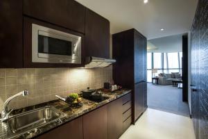 
a kitchen with a stove, microwave, sink and dishwasher at Bab Al Qasr Hotel in Abu Dhabi

