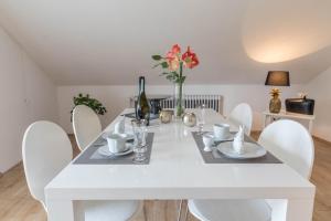 a white dining room with a white table and chairs at Ferienwohnung Lumafe in Überlingen