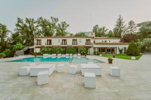 een huis met een zwembad en witte tafels en stoelen bij CAN MARLET MONTSENY Hotel Boutique in Montseny