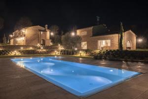 - une piscine en face d'une maison la nuit dans l'établissement Villa Meraviglia Toscana - Homelike Villas, à Foiano della Chiana