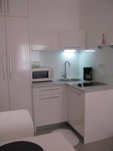 a white kitchen with a sink and a microwave at Downtown Main Street Studio in Zadar