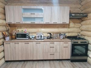 eine Küche mit Holzschränken, einer Mikrowelle und einem Herd in der Unterkunft Cabana Raisa in Valea Moldovei