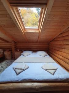 Cama en habitación de madera con ventana en Cabana Raisa, en Valea Moldovei