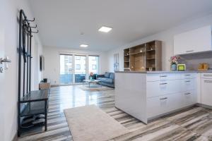 a kitchen with white cabinets and a living room at Apartement Laatzen nähe Messe in Hannover