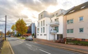 een straat met witte gebouwen en een auto op de weg bij Apartement Laatzen nähe Messe in Hannover