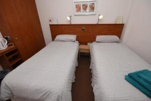 two beds in a small room with a table at Burntisland Sands Hotel in Burntisland