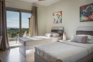 two beds in a bedroom with a view of a balcony at Sailing Villa Kefalonia in Karavadhos