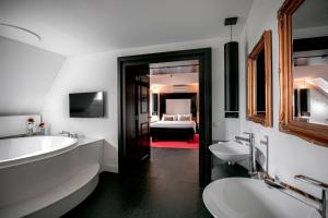 een badkamer met 2 wastafels en een bad en een slaapkamer bij Le Theatre in Maastricht