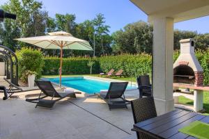 ein Pool mit Stühlen und einem Sonnenschirm neben einem Pool in der Unterkunft Luxury villa Banjole with private pool 200m from the beach in Banjole