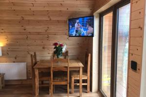 uma sala de jantar com uma mesa e uma televisão na parede em Tollymore Luxury Log Cabin em Kilcoo