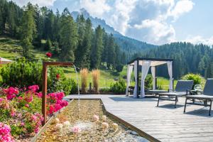 eine Terrasse mit einem Pavillon und Blumen in der Unterkunft Hotel Cristal in Obereggen