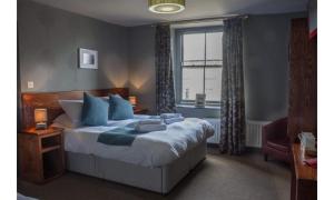 a bedroom with a bed with blue pillows and a window at The Wellwood in Amble