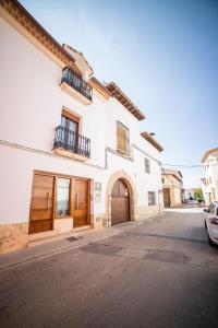 a white building with a gate and a car parked on a street at Apartamentos San Francisco - Centrico in Mota del Cuervo