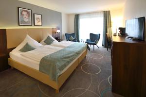 a hotel room with a bed and a desk and a television at Lobinger Parkhotel & Restaurant in Giengen an der Brenz +56 photos