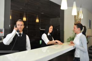 un hombre y dos mujeres parados frente a un mostrador en Hotel Italia, en Múnich