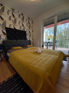- une chambre avec un grand lit et une couverture jaune dans l'établissement Apartament z Wellness Polanki Park Kołobrzeg, à Kołobrzeg