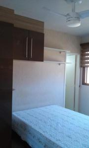 a bedroom with a bed and cabinets and a window at Apartamento em Guarapari in Guarapari