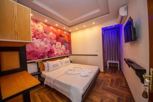 Zimmer mit einem Bett und einem Wandgemälde in der Unterkunft Hotel Legjenda in Shkodra