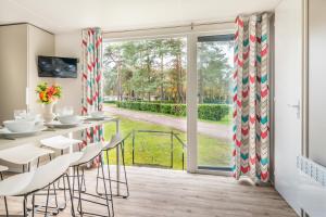 een eetkamer met een tafel en stoelen en een groot raam bij Chalet O'hara in Bilthoven