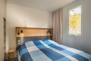 a bedroom with a blue and white bed and a window at Chalet O'hara in Bilthoven +3 photos
