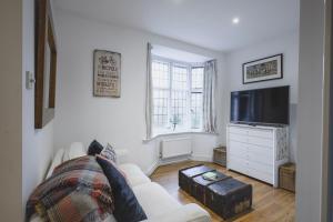 a living room with a white couch and a tv at The Old Cook's House in Hindhead