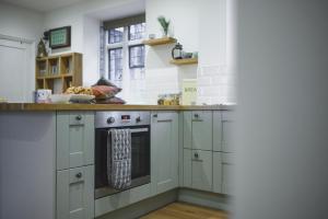 una cucina con armadi bianchi e forno con finestra di The Old Cook's House a Hindhead