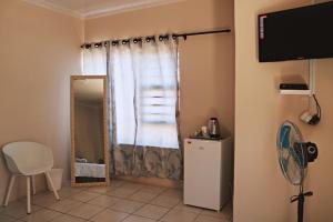 a room with a window with a mirror and a refrigerator at My Guesthouse in Kimberley