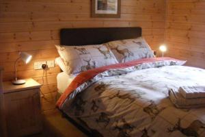 1 dormitorio con 1 cama en una pared de madera en Glas Doire Lodge, Glen Roy Nature Reserve, en Roybridge