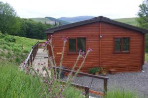 een houten hut met een hek ervoor bij Glas Doire Lodge, Glen Roy Nature Reserve in Roybridge