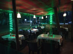 a restaurant with tables and chairs with green lights at Mama Mids Home in Morjim
