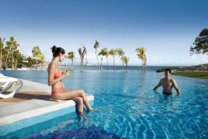 a man and a woman sitting in a swimming pool at Riu Palace Peninsula - All Inclusive in Cancún