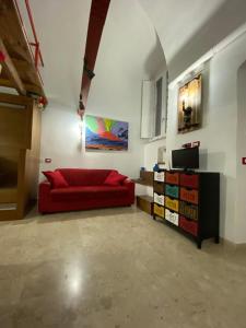 un soggiorno con divano rosso e TV di Casa Margot a Napoli