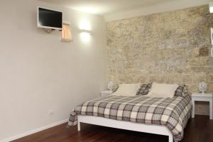a bedroom with a bed and a stone wall at Alla Corte del Conte in Conversano