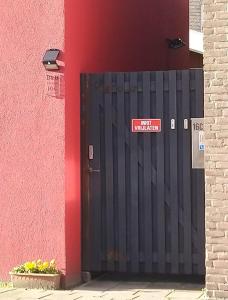 a black gate with a sign on it next to a building at B&B 16C Maassluis NL in Maassluis