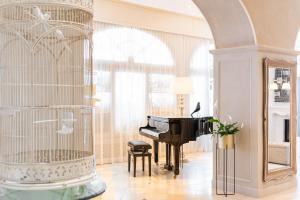 una stanza con pianoforte e gabbia per uccelli di Grand Hotel Fasano & Villa Principe a Gardone Riviera