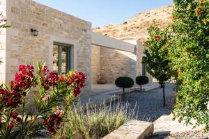ein Steinhaus mit roten Blumen im Garten in der Unterkunft Villa Galliki in Kamilari