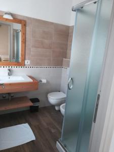 a bathroom with a toilet, sink, and shower at Etesia in Olbia
