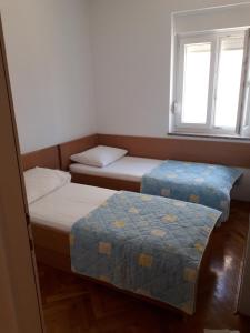 2 Betten in einem Zimmer mit 2 Fenstern in der Unterkunft Apartments Miljenko in Novalja